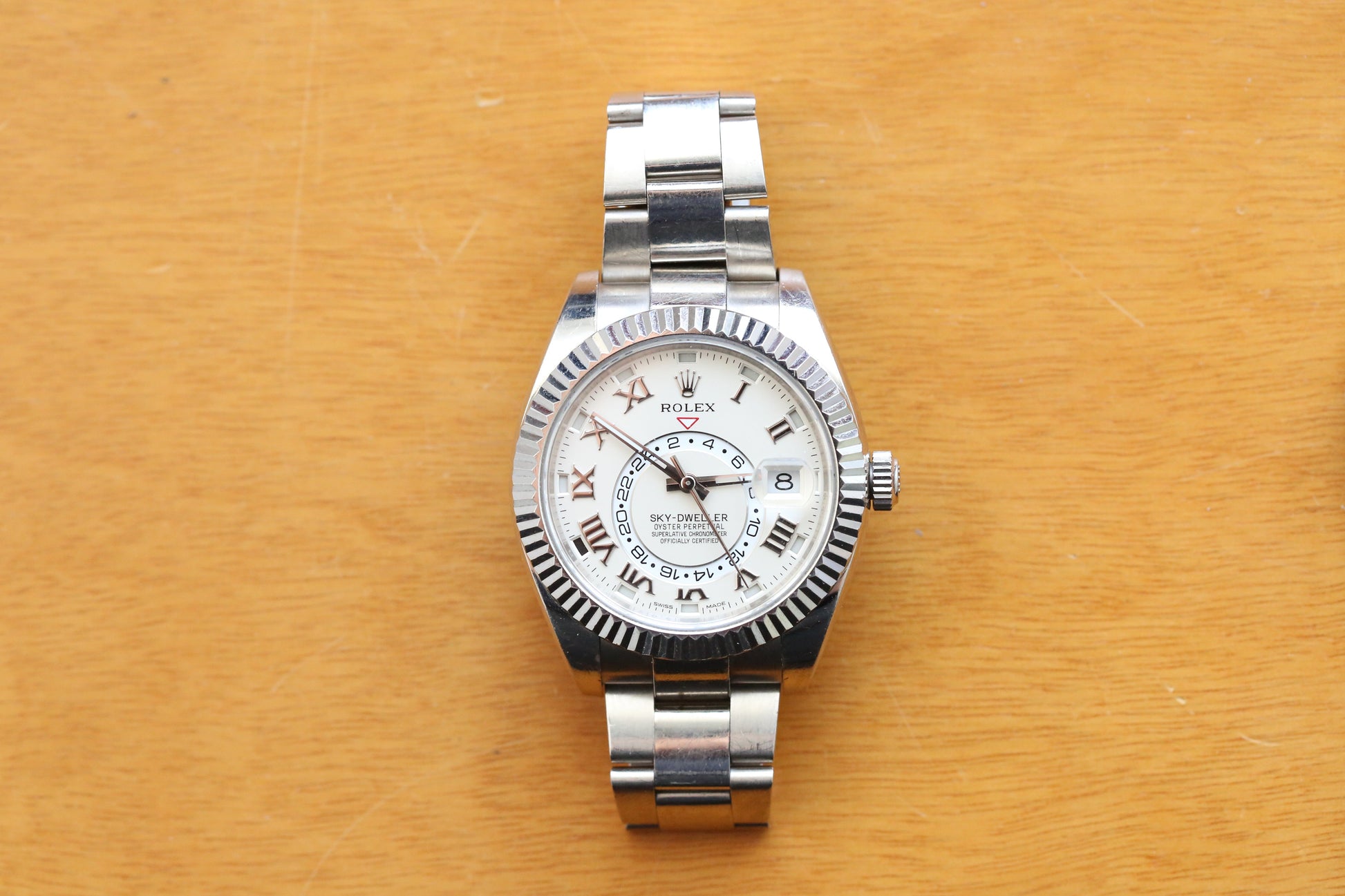 Silver watch with a white face on a wooden surface