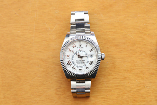 Silver watch with a white face on a wooden surface